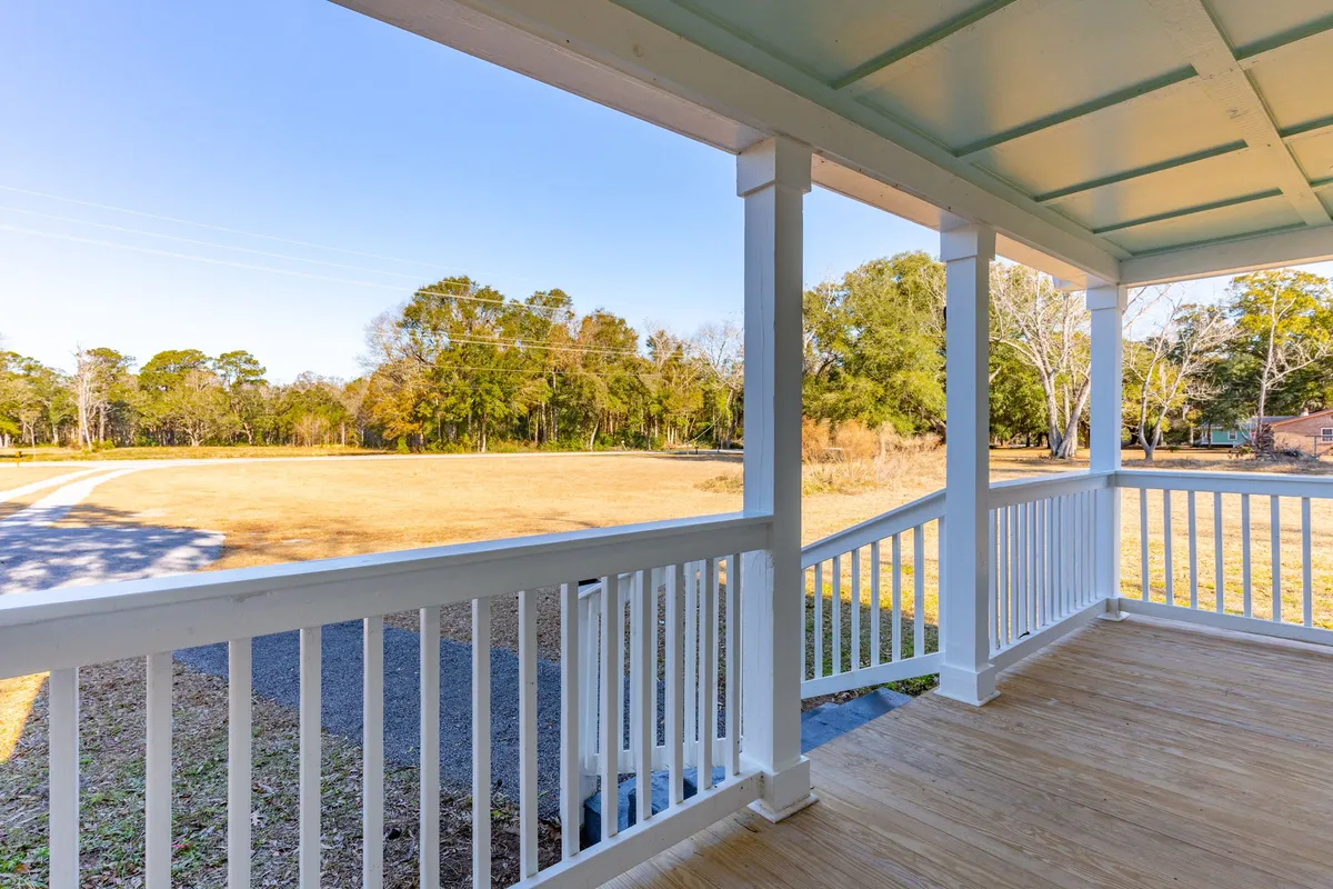 A tranquil view from the porch, showing wooden railings and open vistas of the surrounding landscape. The scene captures the expansive feel of the outdoor living area and suggests the enjoyment of wildlife, sunsets, and quiet reflection.