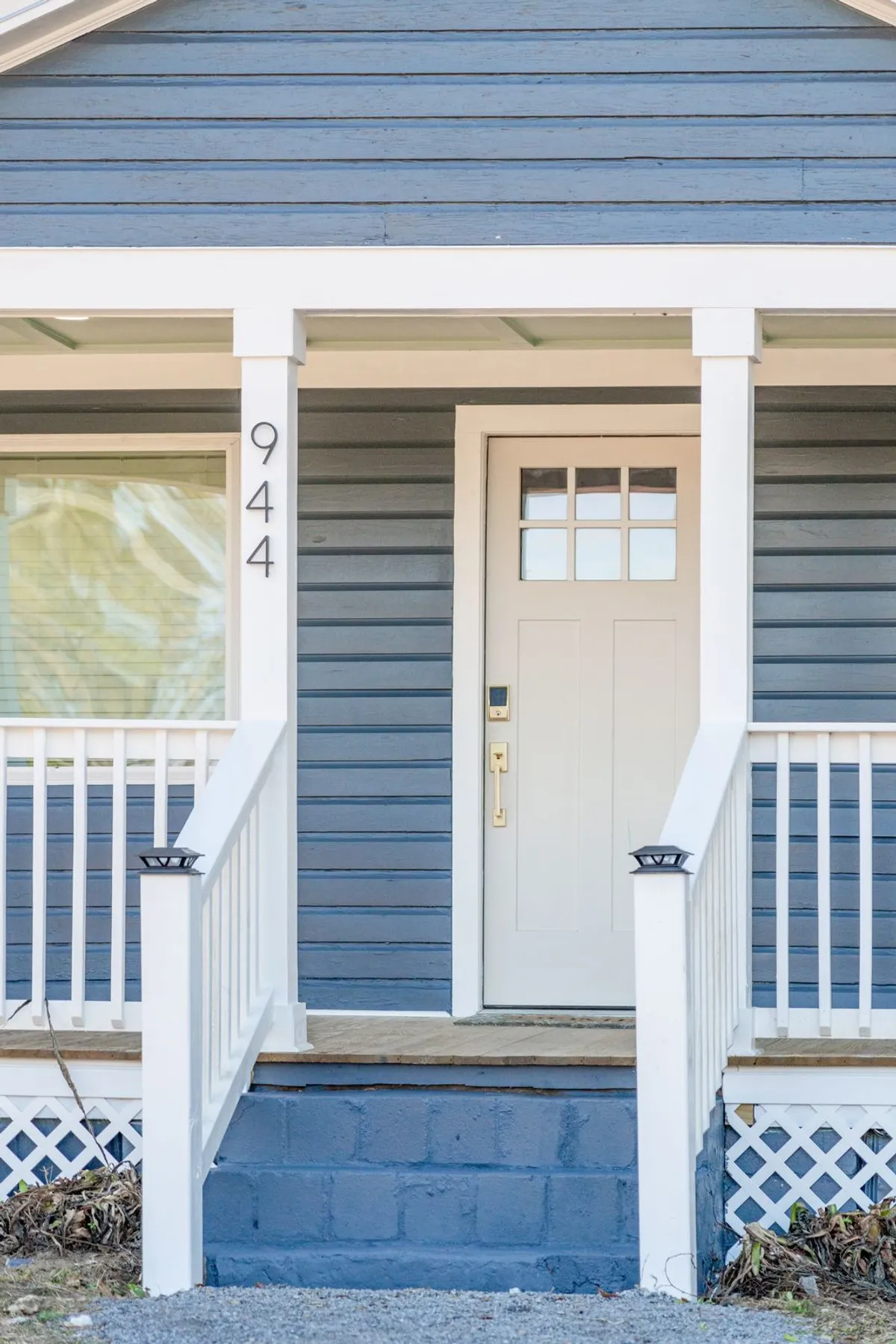 The photo highlights the welcoming front door, porch steps, and a cozy entryway, suggesting a warm invitation to enter the home. The porch is subtly decorated and exudes a sense of comfort and charm.