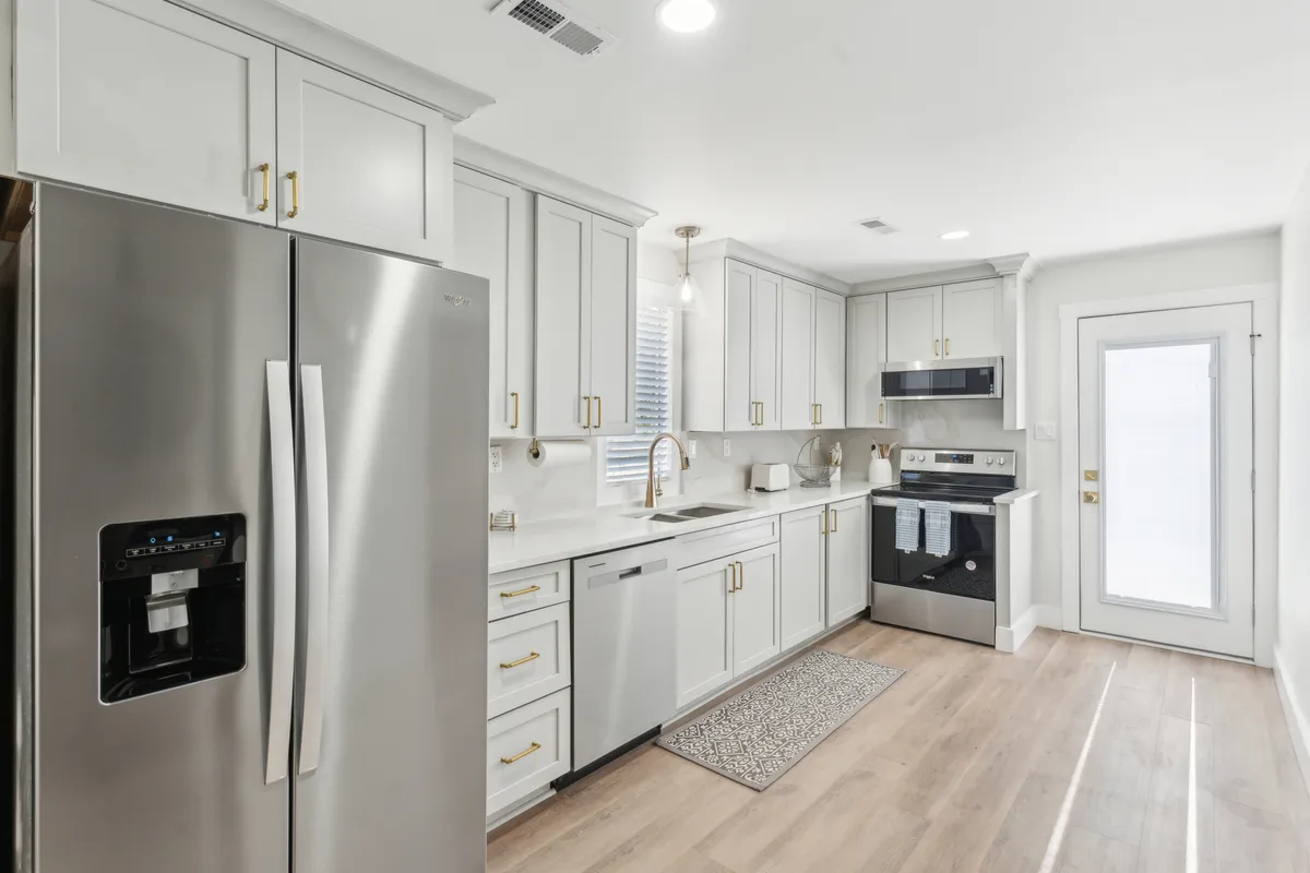 This image showcases a modern kitchen featuring a stainless steel refrigerator, sleek cabinetry, a spacious kitchen island, and a sink with a contemporary faucet. The space is open and inviting, with ample room for cooking, prepping, and socializing.